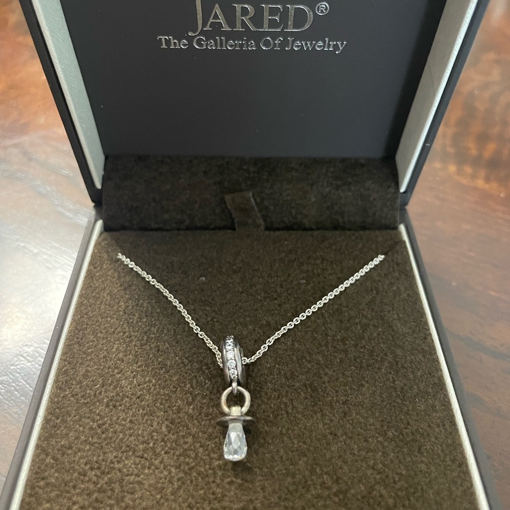 Silver necklace with a circle at end and pacifier at end of circle